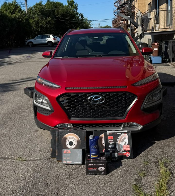 Hyundai Kona rouge, ses disques et plaquettes neufs posés devant.